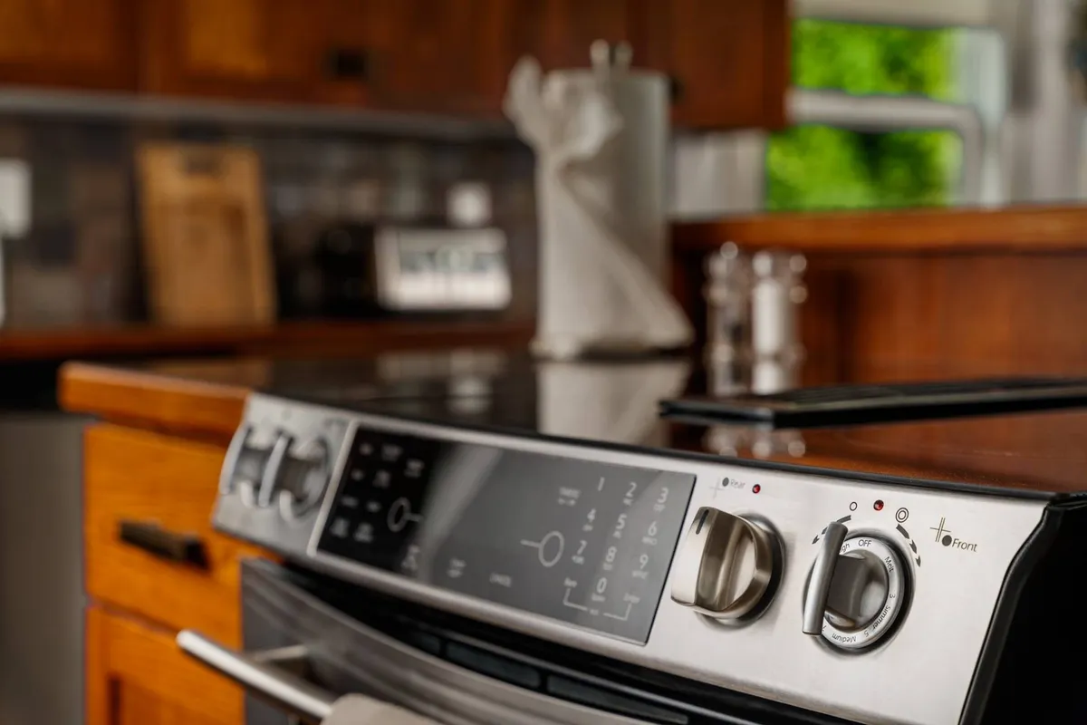 A view of the kitchen with modern cabinetry and stove controls, kitchen utensils ready for use. The space is inviting and clearly designed for preparing family meals or snacks after time spent outside.